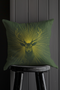 A pillow cover with a majestic stag illustrated in metallic gold on deep moss green fabric. Gleaming rays extend outward from the deer's head, with small golden stars dispersed throughout.